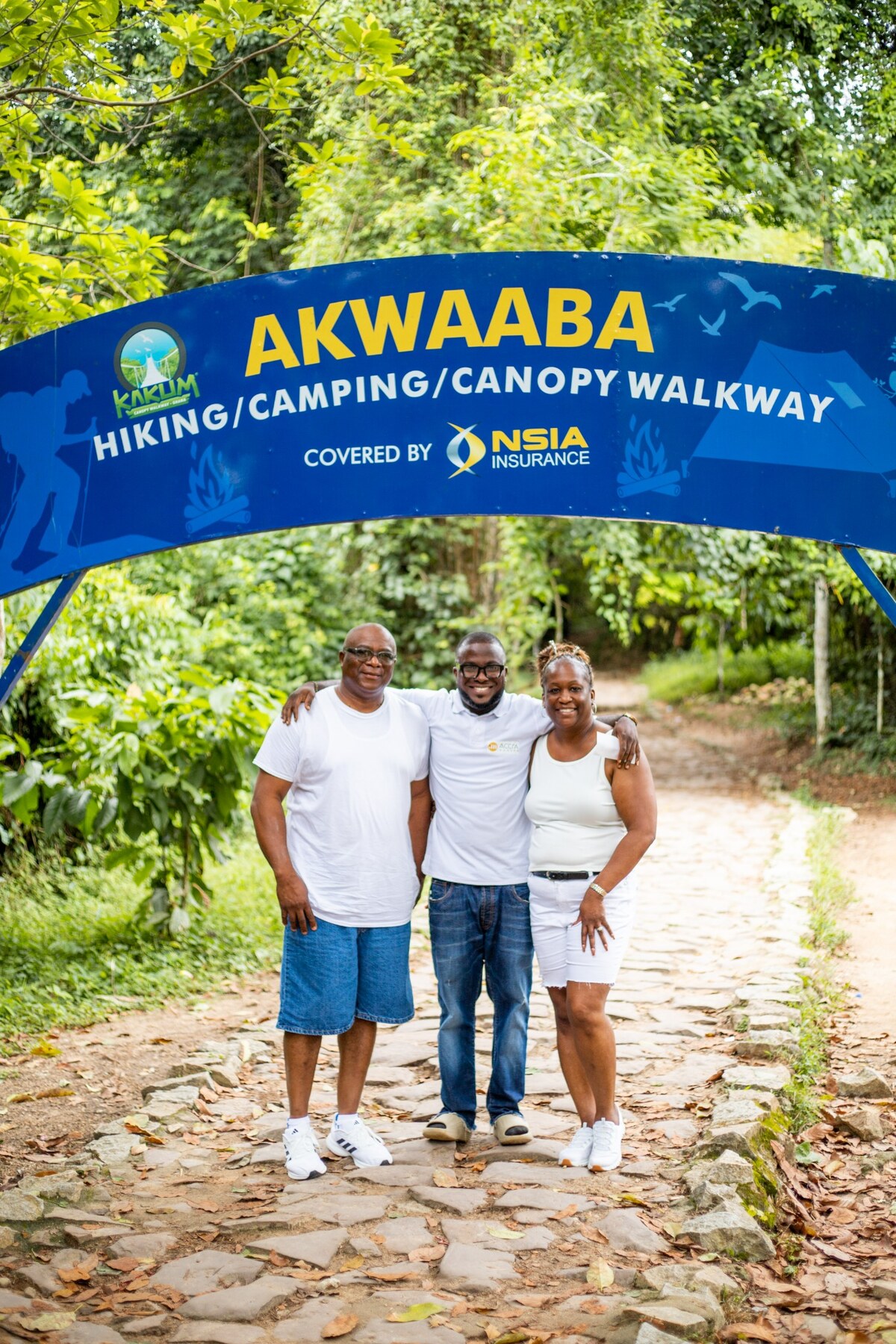 Three Accra Modern guests beneath the Kakum canopy walkway welcome sign
