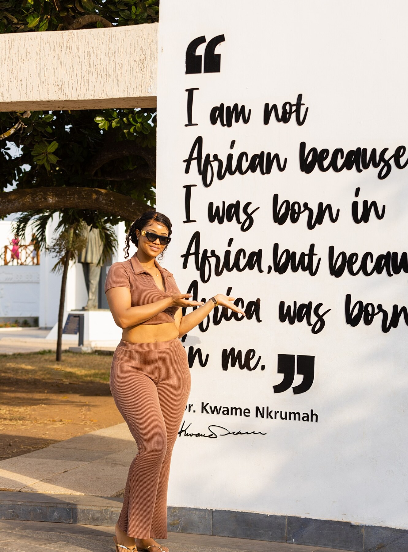 A guest standing beside a Kwame Nkrumah quote in Accra